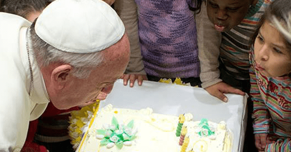 Pope Francis blows out the candles on a cake presented to him at a Vatican run children's care center